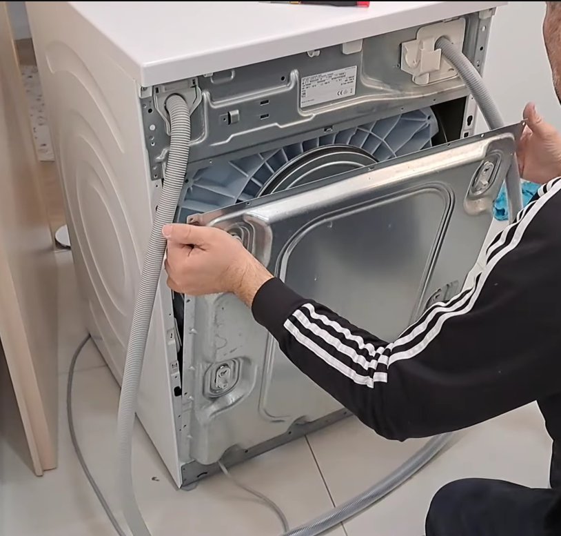 Technician inspecting the back of a Bosch appliance checking internal hoses and connections for water leak causing E15