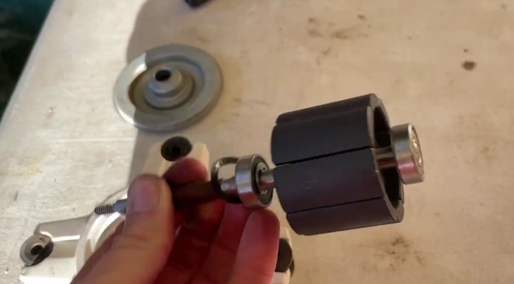 Close-up of AC fan motor rotor and bearing assembly held in hand on workbench — worn bearings are a common cause of E7