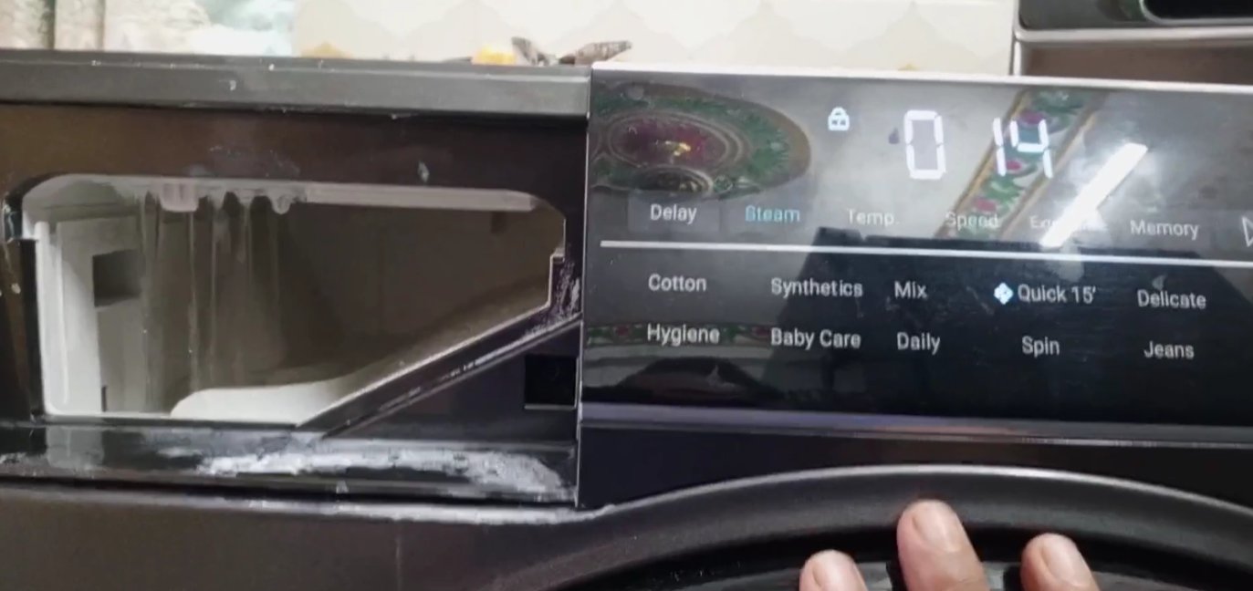 Washing machine detergent drawer pulled open showing compartments — front-load washer maintenance guide