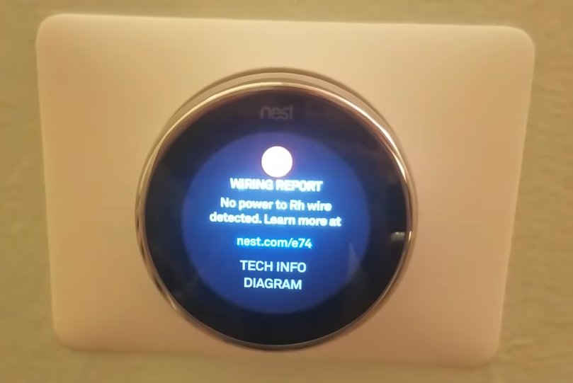Google Nest thermostat mounted on white wall showing Wiring Report screen with No power to Rh wire detected error message and links to nest.com/e74 Tech Info and Diagram