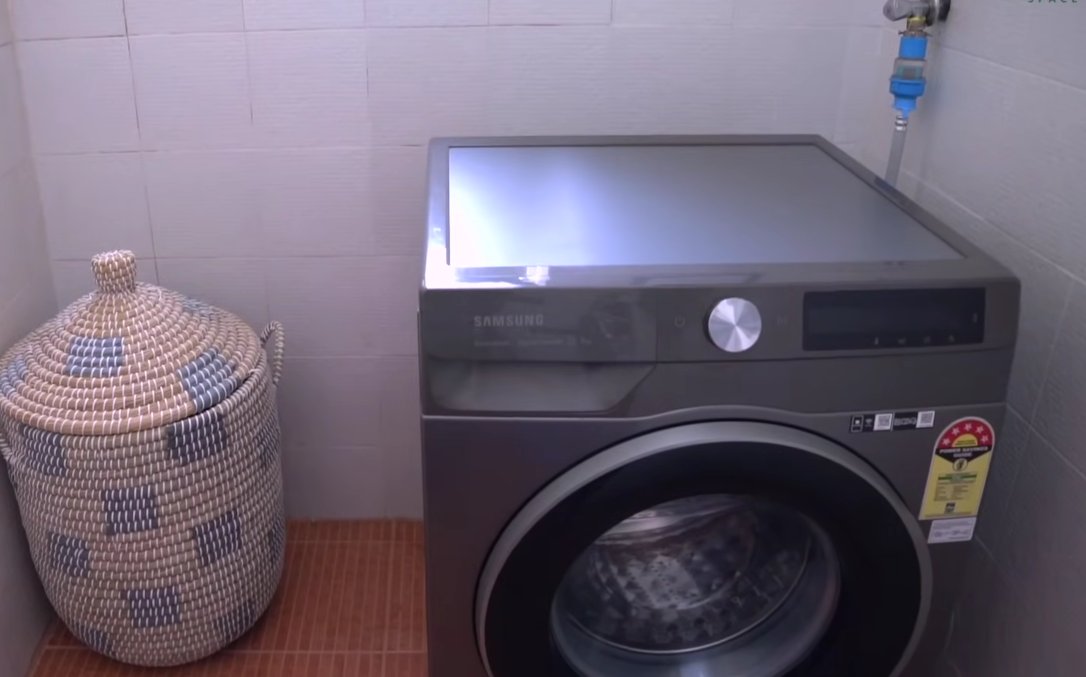 Samsung washing machine installed with water inlet hose and tap connection visible at the wall