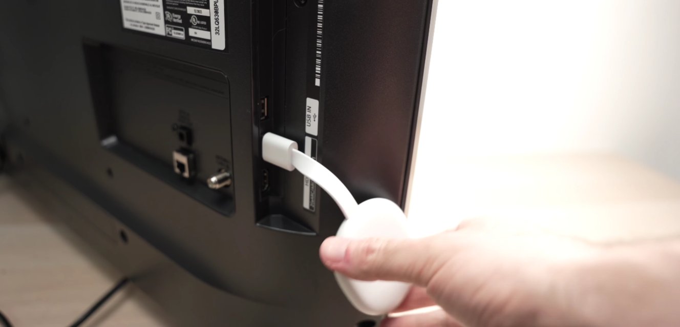 Hand disconnecting a white USB cable from the rear USB IN port of a Samsung TV showing the back panel with HDMI and other ports visible during the device disconnection step