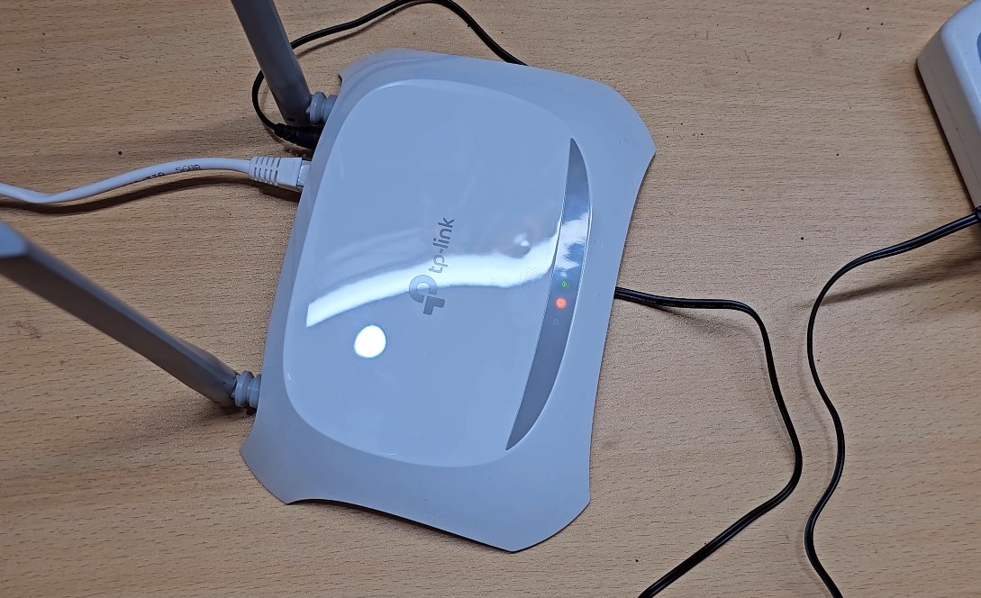 Close-up of a TP-Link router top panel showing an orange/amber WAN LED glowing next to a green WiFi indicator