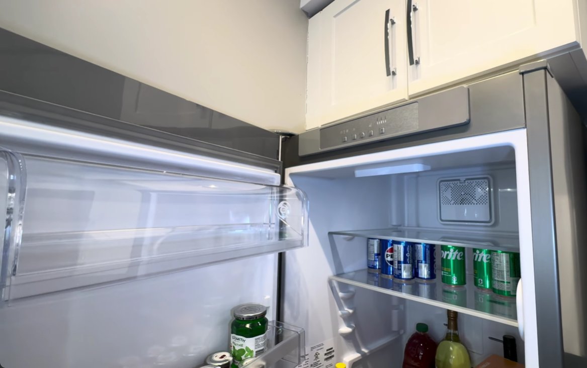 Whirlpool refrigerator interior open showing control panel at the top with temperature and alarm buttons visible